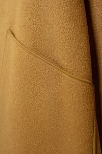 Macro view of premium camel wool fabric texture and precise stitching on the coat pocket