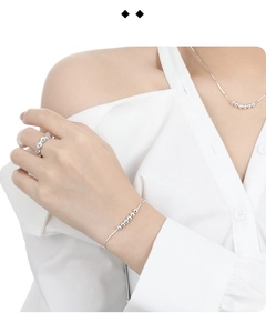 Détail du collier à perles argentées et bague ondulée portés par un mannequin élégant
