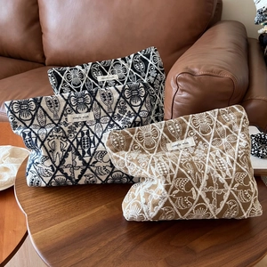 Macro detail of intricate embroidery and cotton linen texture on cosmetic pouches