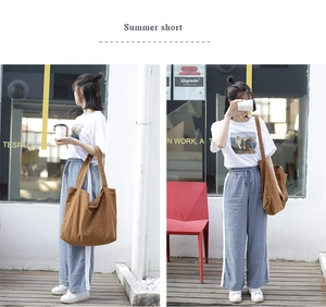 Detail of a large brown canvas tote bag paired with a casual summer T-shirt and blue pants