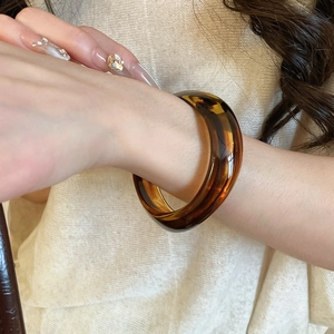 Close-up of vintage amber translucent acrylic wide cuff bracelet worn on a wrist