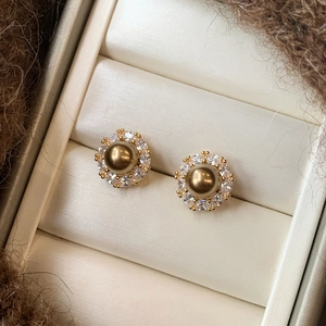 Macro shot of vintage champagne pearl earrings with crystal halo in a velvet jewelry box