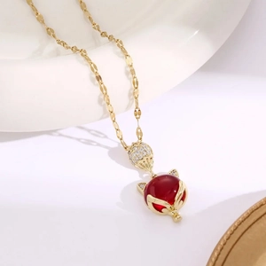 Detail shot of the fox pendant with deep red resin stone and zircon micro-pave in gold finish