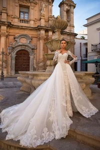 Détails des manches en dentelle blanche et broderies délicates d'une traîne de mariée
