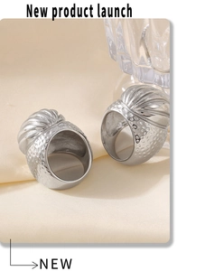 Macro detail of silver ribbed twist rings with hammered texture on elegant beige fabric