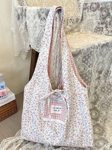 Floral canvas tote bag with bow and lace detail hanging on a wooden chair back