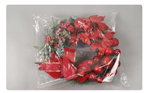 Detail of a red Christmas wreath with poinsettias, ornaments and silk bow in packaging