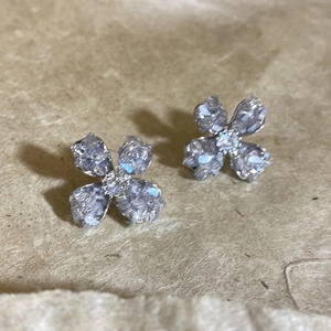 Macro detail of silver four-leaf clover stud earrings with sparkling clear crystals