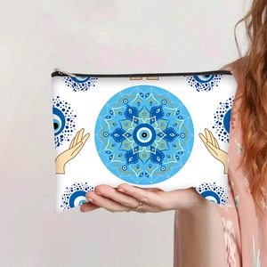 Detail of hand-held makeup bag featuring blue evil eye mandala print and zipper closure