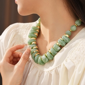 Gros plan d'un collier vintage en perles vertes avec des entretoises dorées sur un modèle
