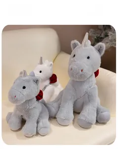 Three sizes of plush unicorns with red roses and decorative ribbons on a soft sofa