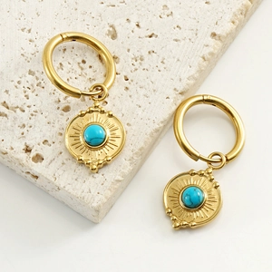 Detailed macro view of 18K gold stainless steel earrings with turquoise sunburst pendant