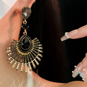 Close-up of vintage gold teardrop tassel earrings with black and clear crystals