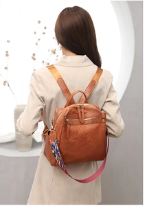 Detail of brown leather backpack featuring a colorful geometric woven shoulder strap