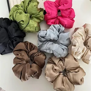 Detailed view of seven colorful silk satin scrunchies with elegant glossy texture