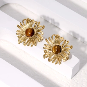 Gold flower stud earrings with tiger eye stone center on minimalist white pedestal