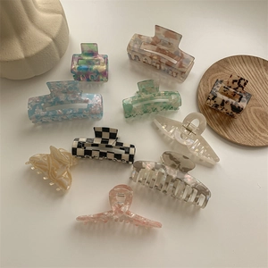 Close-up of acetate shark hair clips with tortoiseshell and marble patterns on a tray