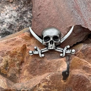 Vintage pirate skull and crossbones brooch in distressed silver finish on red rock