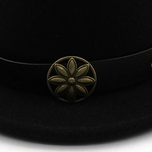 Close-up of leather band with vintage bronze flower buckle on black wool top hat