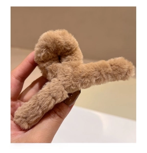 Détail d'une pince à cheveux en fausse fourrure beige montrant sa texture douce