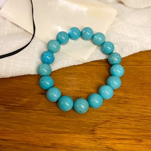 Macro shot of turquoise beaded elastic bracelet with natural texture on a wooden background