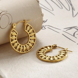 Macro detail of gold-plated stainless steel hoop earrings with hollow leaf pattern texture
