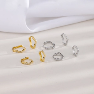Detailed view of wave-shaped zircon hoop earrings in gold and silver finishes