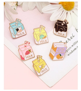 Detail shot of creative enamel milk carton pins on a decorative floral background