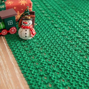 Christmas green knitted table runner with festive holiday decor on wooden table