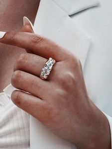 Close-up of a silver-toned ring with unique molten lava texture worn on a model's finger
