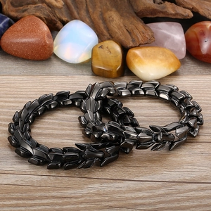 Detailed view of interlocking black dragon scale link bracelets on a rustic wood surface