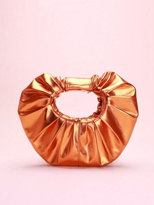 Detail of metallic orange pleated clutch bag with circular handle on pink background