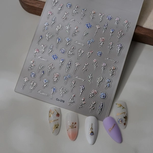 Macro view of 5D embossed flower nail stickers with silver foil edges on manicured tips