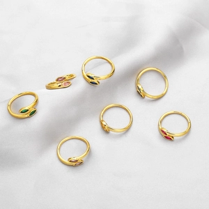 Set of seven gold open rings with colorful marquise-cut stones on white silk