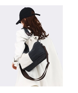 Detail of a large two-tone canvas bucket bag with adjustable shoulder strap and metal rings