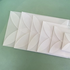 Dettaglio di buste traslucide in carta velina con eleganti lembi a forma di petalo bianco