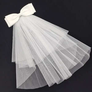 Short double-layered white wedding veil with large satin bow and pearl accents on black ground