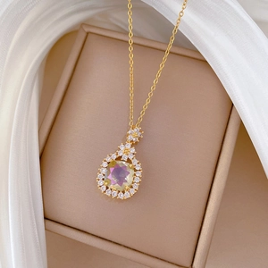 Detailed close-up of gold titanium necklace with oval gemstone and flower accents