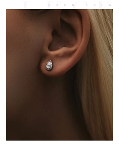 Macro shot of a pear-cut moissanite halo stud earring worn on a female model ear