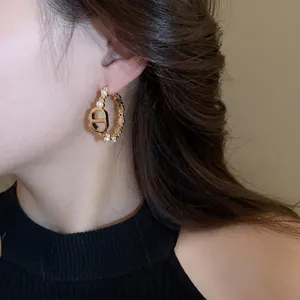 Gold-plated pig-nose hoop earrings with CD logo and white pearls on female model