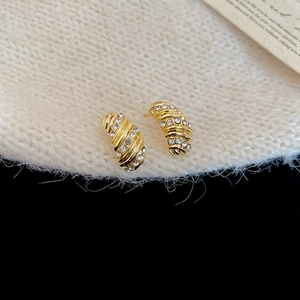 Detail of gold C-shaped twisted earrings with two rows of sparkling clear zircons