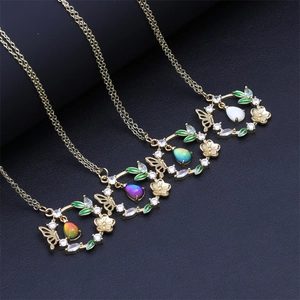Détail de colliers dorés avec pendentifs papillon et fleurs ornés de zircons blancs