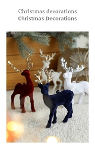 Detail of flocked Christmas reindeer ornaments with glitter antlers on snow background
