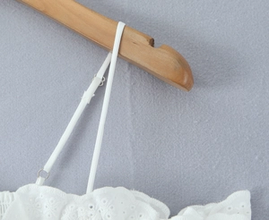 Detalle del bordado de encaje blanco y tirantes ajustables en un top de estilo francés