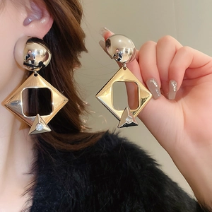 Detail of gold geometric earrings with rhinestones showing the elegant hanging design