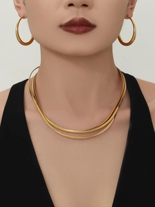Collier ras du cou doré poli à double couche et boucles d'oreilles créoles sur un mannequin