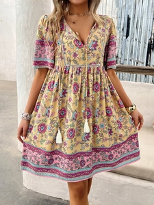Detail of bohemian yellow floral dress with V-neckline and decorative tassel drawstrings