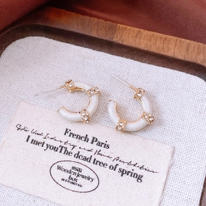 Close-up of French vintage C-shaped earrings with white enamel and sparkling diamonds