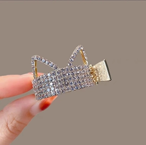 Close-up of golden claw clip with silver rhinestone cat ear design and high-gloss finish