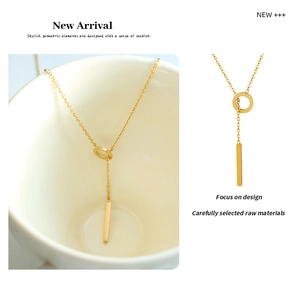 Macro detail of 18K gold titanium pendant necklace with ring and vertical bar tassel